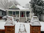 白雪覆盖的屋顶和树木，与风景如画的平房一起，描绘出一个宁静的冬季场景