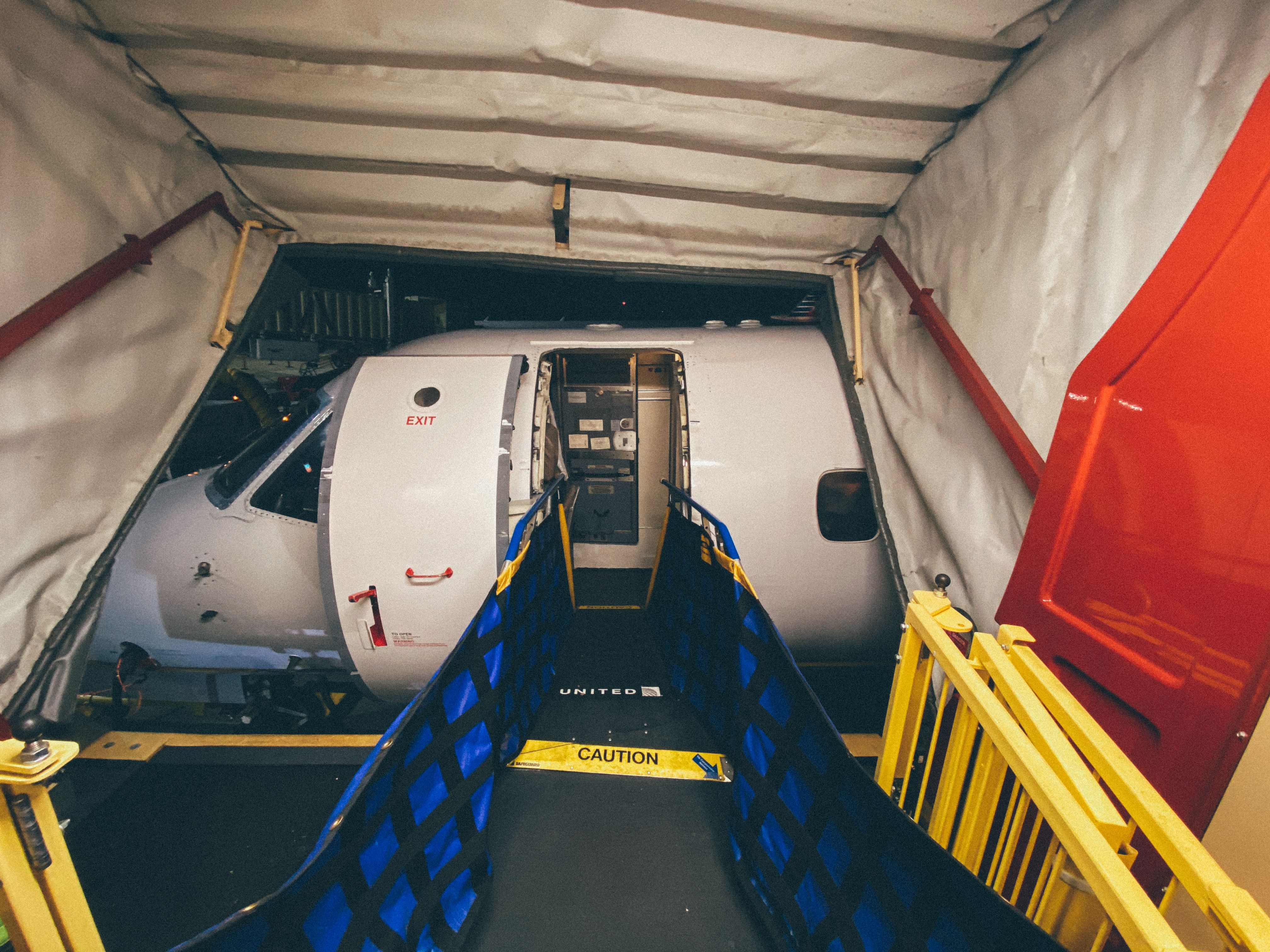 Aircraft parked at a gate with its door open and a boarding ramp leading to the entrance