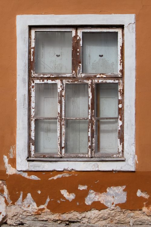 Free A rustic wooden window on a weathered orange wall in Tallinn, Estonia, highlighting historical charm. Stock Photo