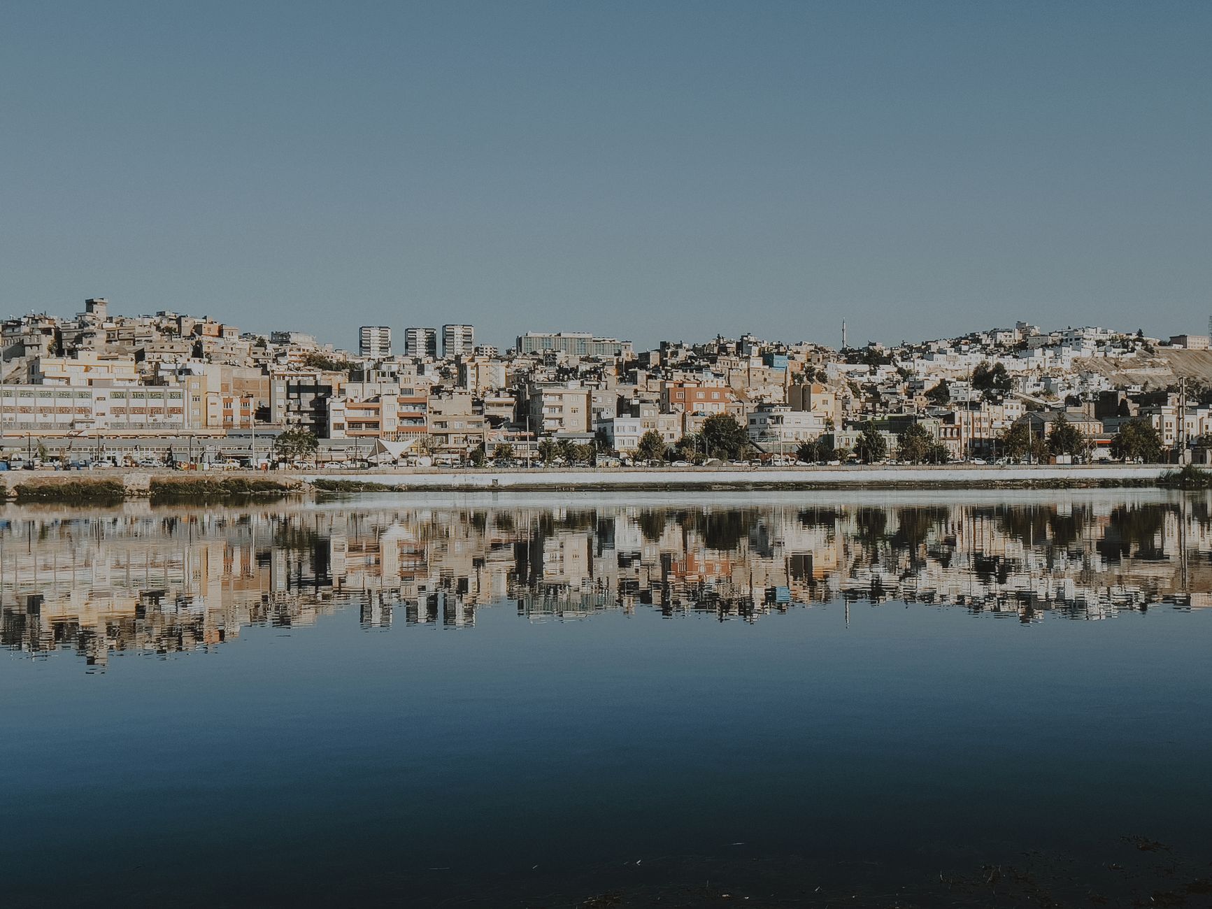 A picturesque cityscape reflecting on the calm water, showcasing urban architecture.