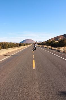 Person jumping on a deserted highway in Strawberry, Arkansas. Bright, sunny day with clear blue sky.