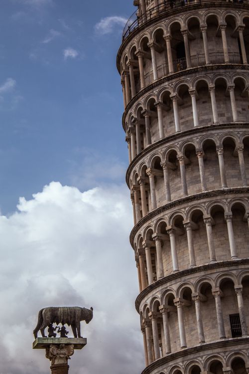 Free The Leaning Tower of Pisa with statuettes and columns under a clear blue sky. Stock Photo