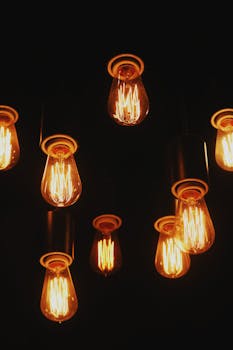 Multiple vintage Edison lightbulbs glowing warmly against a dark backdrop.