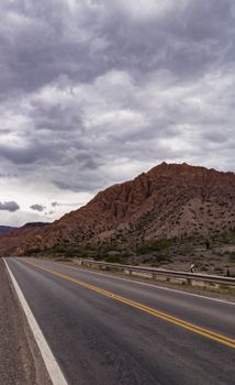 Dramatic sky over the Quebrada de Humahuaca in Jujuy, Argentina, featuring a winding road and rocky mountains.