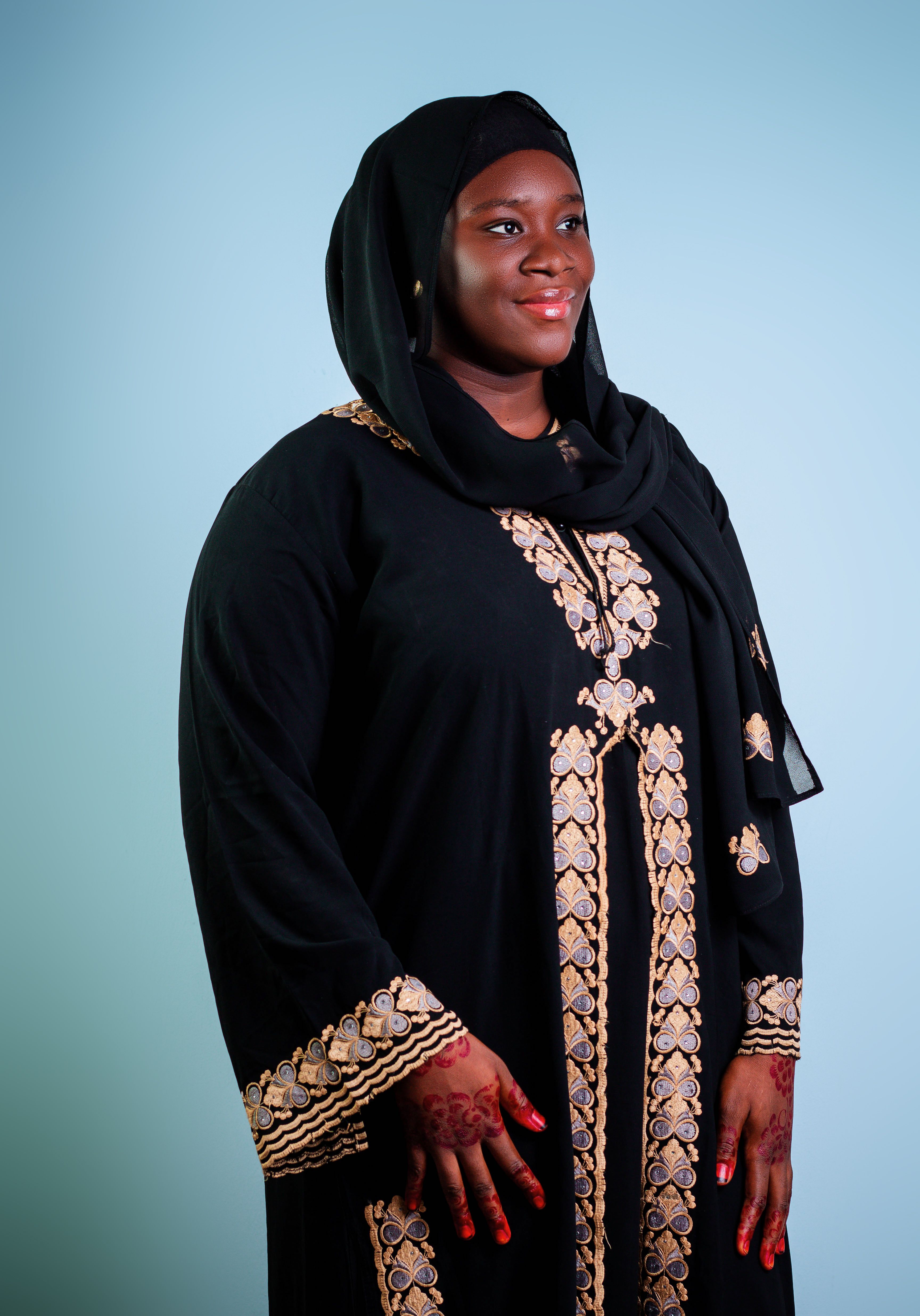 Portrait of a woman in a black abaya with gold embroidery, showcasing traditional fashion.