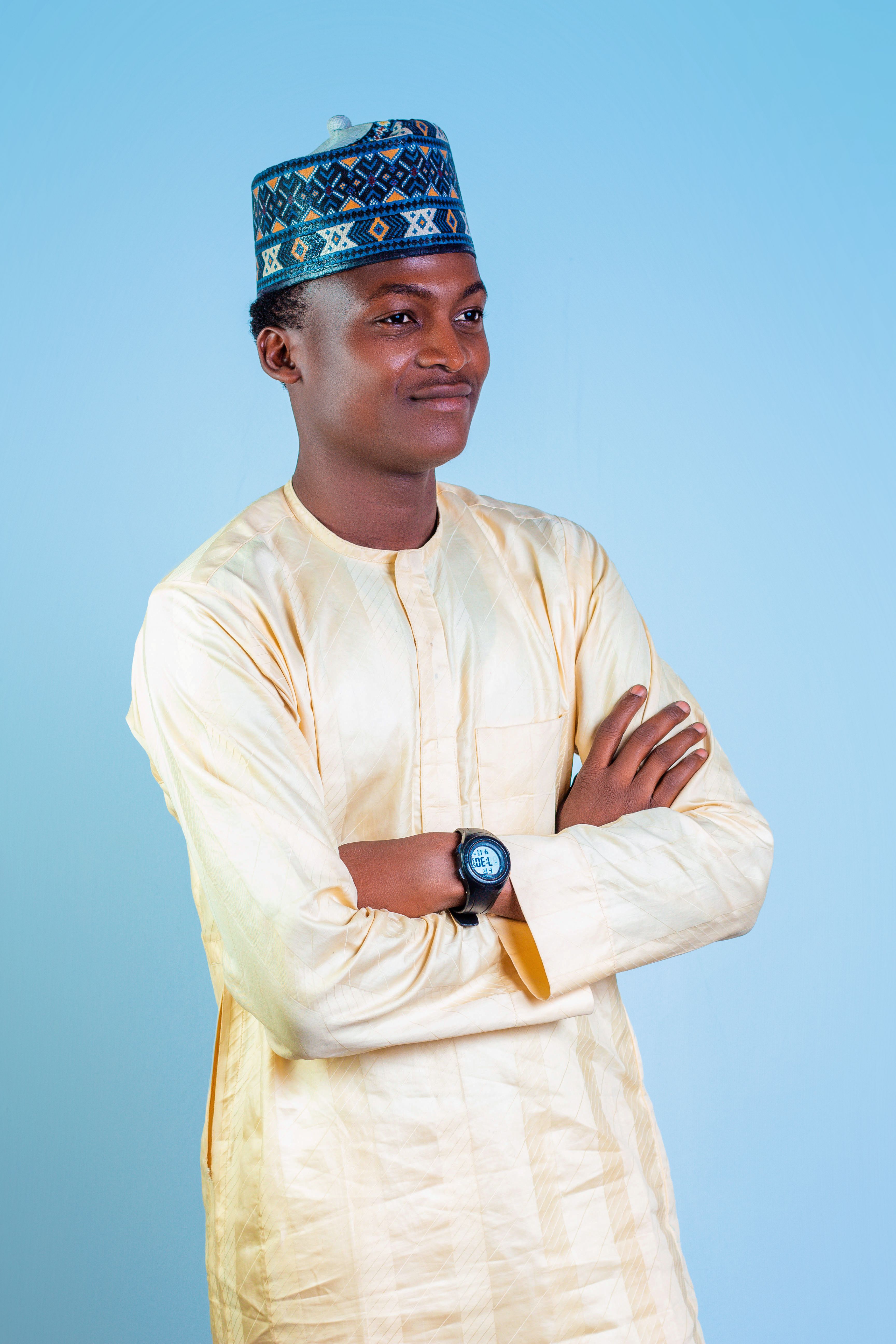 Portrait of a smiling young man in traditional attire with arms crossed.
