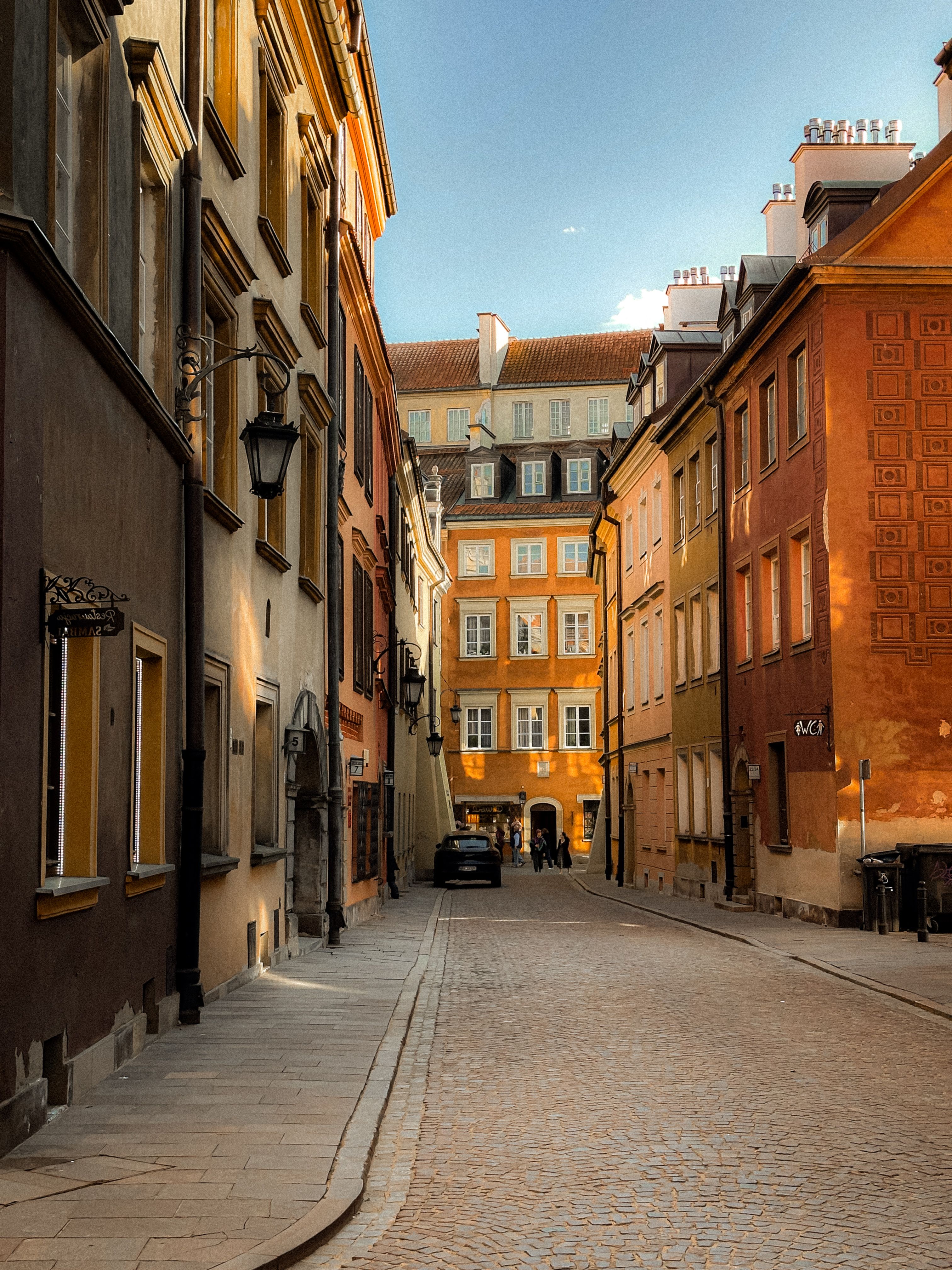 Charming street in Warsaw's Old Town with colorful historic buildings at sunset, offering a warm and inviting atmosphere.