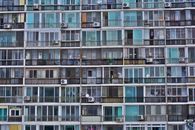 Facade of contemporary residential multistage house with many apartments representing fenced terraces and windows near outdoor air conditioning units in town in daylight