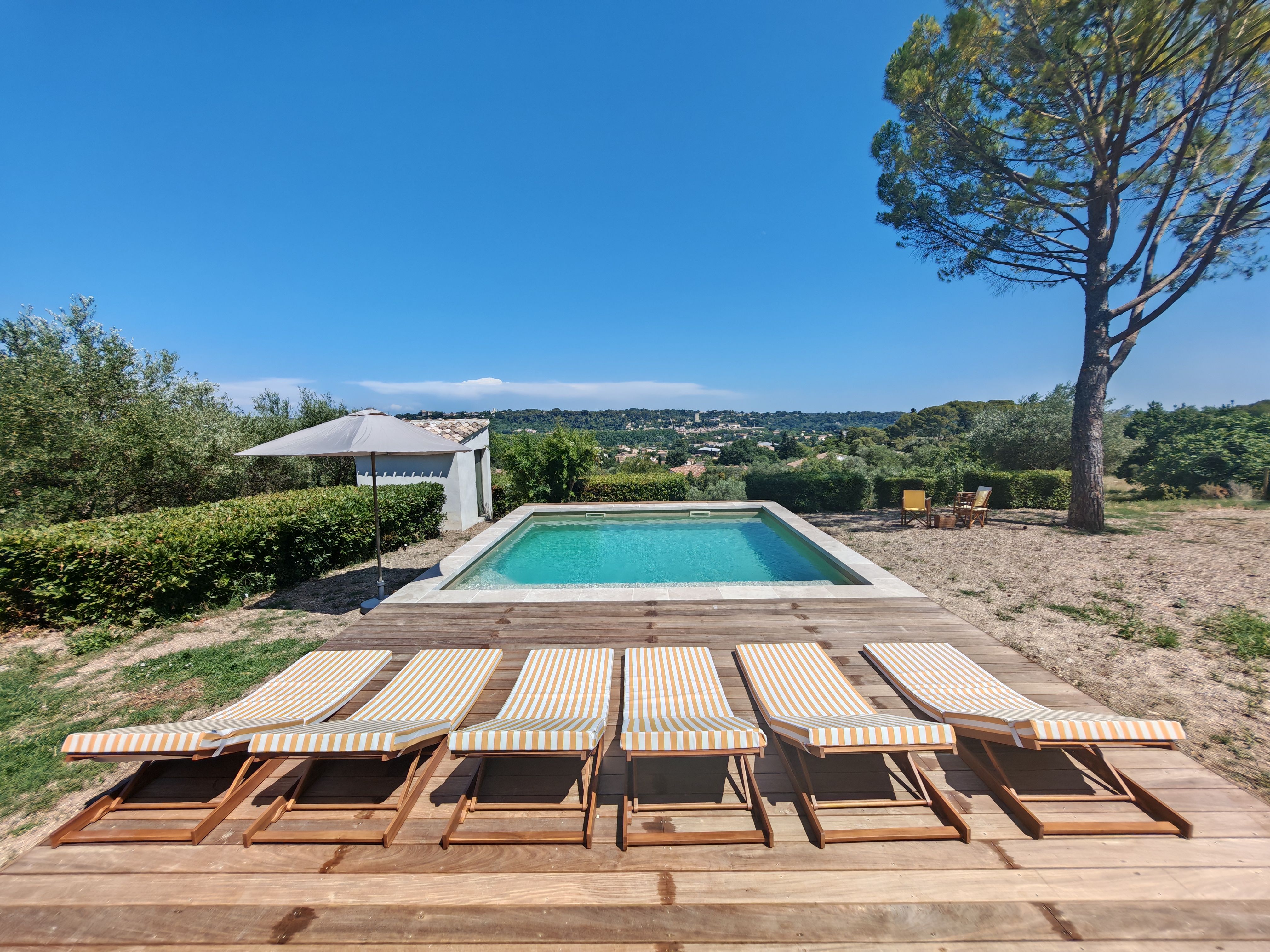 Outdoor swimming pool surrounded by sun loungers on a warm afternoon