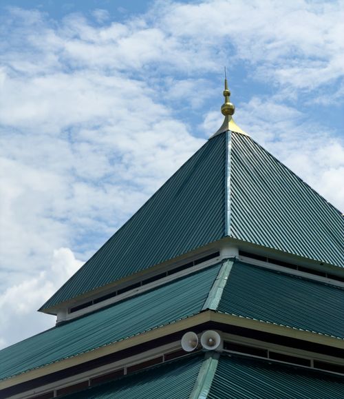 Free Ornate green metal mosque roof with golden finial against a bright blue sky in Kuching, Malaysia. Stock Photo