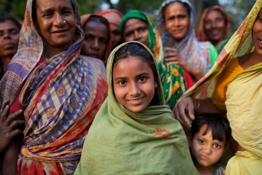 Smiling girl among women showcases empowerment in Kishoreganj, Bangladesh.