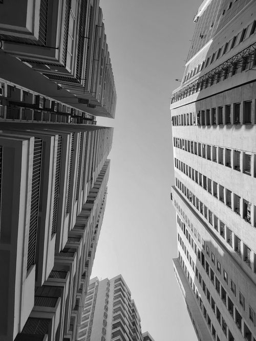 Free A monochrome view of towering buildings converging against the sky. Stock Photo