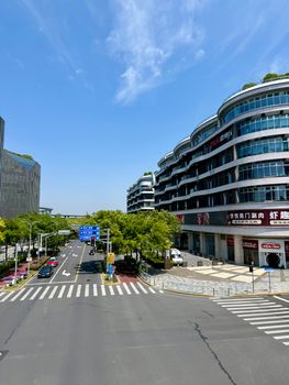 Bright urban street scene in Shanghai with modern architecture under a clear blue sky.