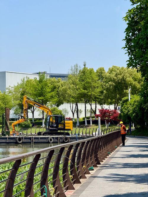 Free A worker oversees construction by the water in a scenic Shanghai park. Stock Photo