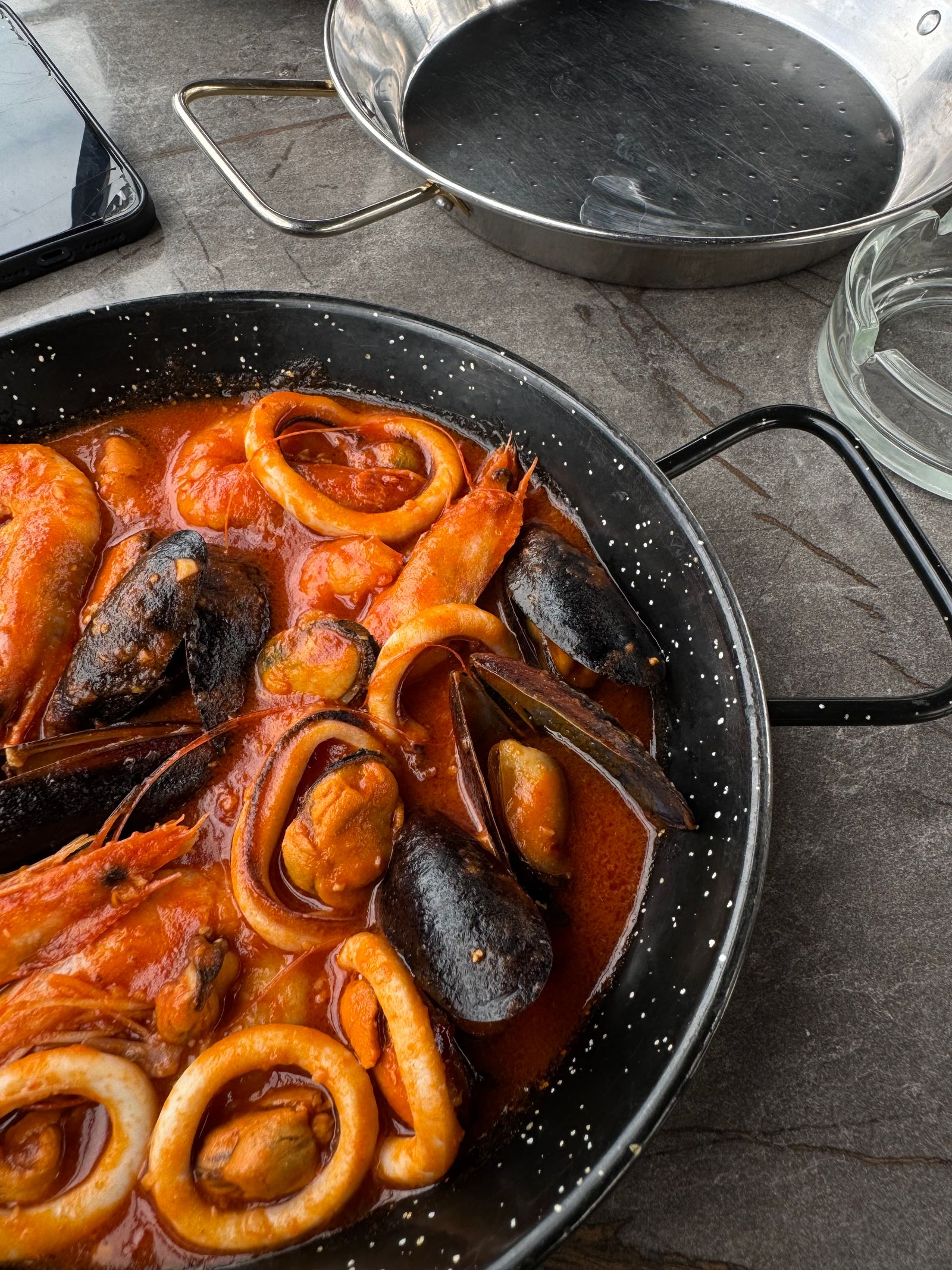 A vibrant dish of seafood paella featuring mussels, shrimp, and squid rings in a rustic kitchen setting