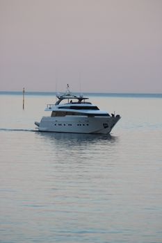 Elegant yacht cruises on serene waters near Portofino, Italy, during a tranquil sunset.