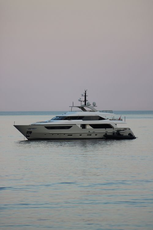 Free A serene view of a luxury yacht floating on calm waters near Portofino at dusk, under a pastel sky. Stock Photo