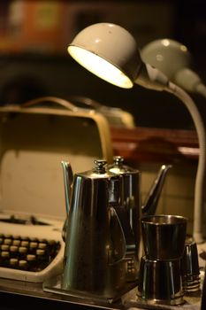 A nostalgic vintage desk with a typewriter, lamp, and coffee set, creating a retro atmosphere.