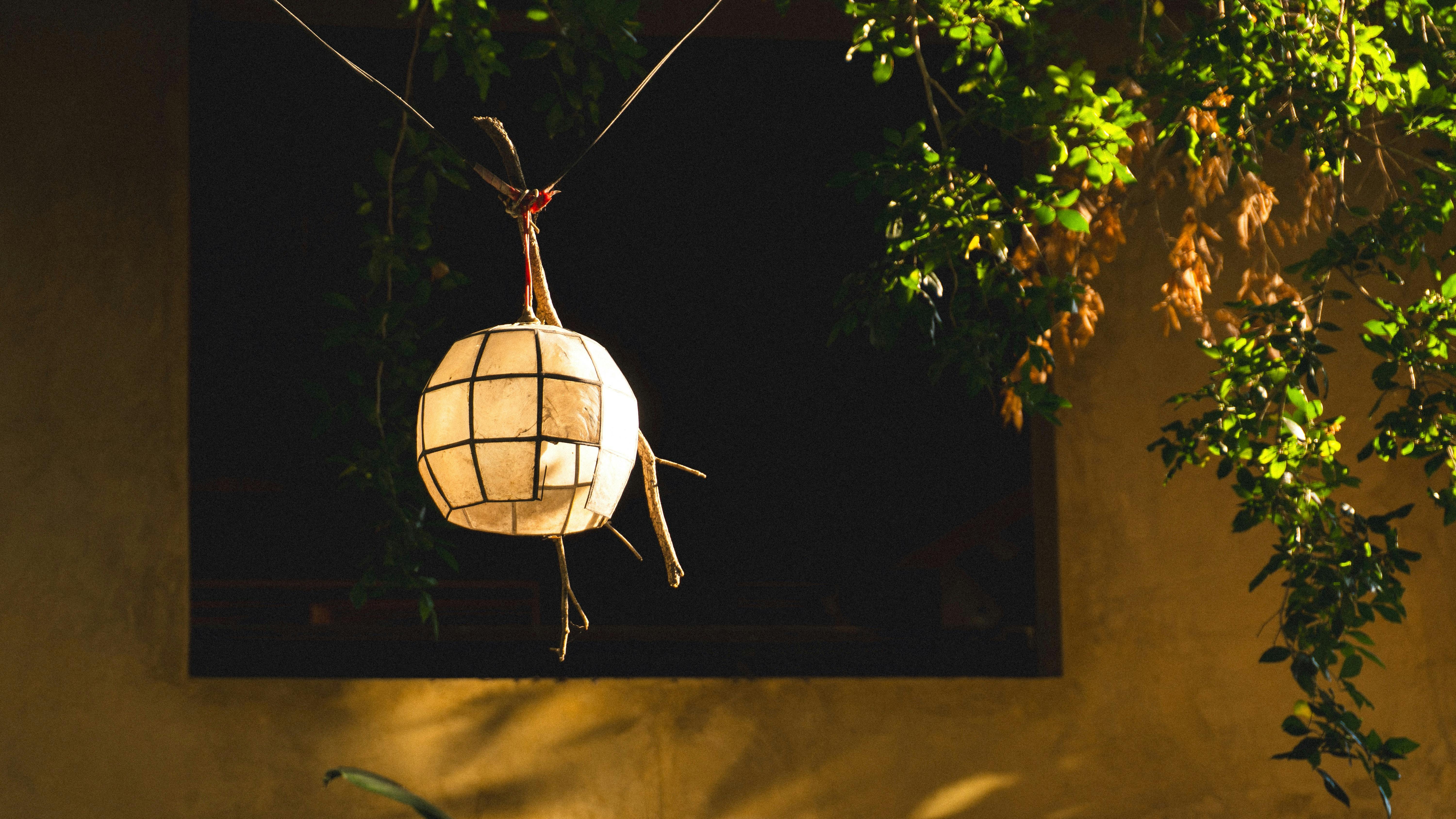 iluminação decorativa artesanal com figura de um inseto feito de papel, centro de atenção em um espaço externo à noite
