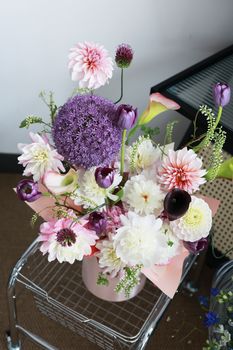 A beautiful floral arrangement featuring colorful dahlias, alliums, and tulips in a modern setting.