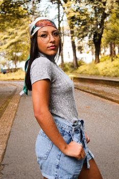 一位穿着休闲服的年轻女子在户外小径旁自信地摆着姿势，两旁树木林立