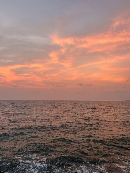 Free A breathtaking orange and pink sunset over the ocean, depicting serene coastal beauty. Stock Photo