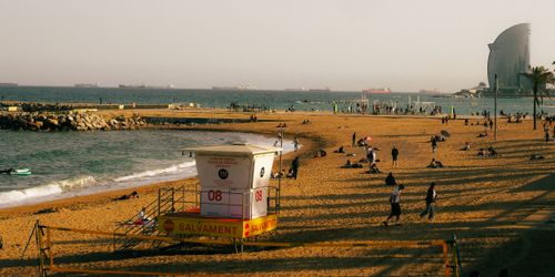 Free People enjoying a sunny day at Barcelona beach with a view of the sea and iconic tower Stock Photo
