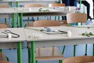 Rows of classroom tables with flowers and graduation caps in an indoor setting, suggesting a recent ceremony.