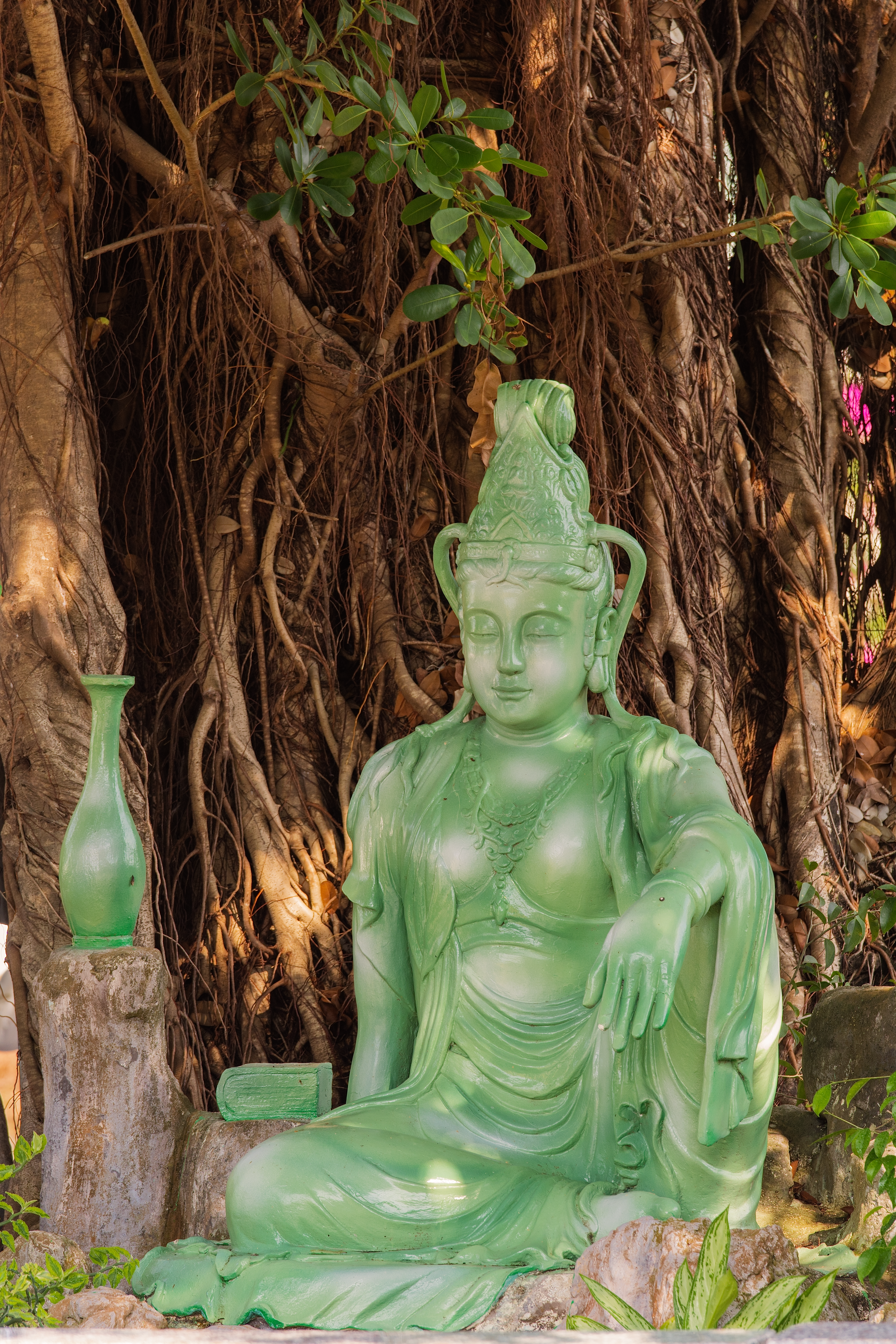 Serene Green Buddha Statue Against Tree Background · Free Stock Photo