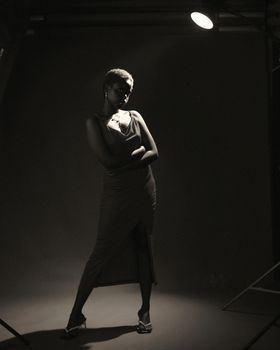 Stylish black and white portrait of a woman in a dimly lit studio.