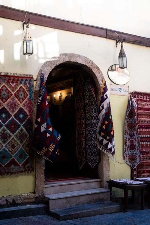 Free Charming entrance of a rug shop with vibrant traditional carpets hanging, creating a cozy ambiance. Stock Photo