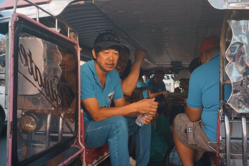 Free Group of men sitting inside a traditional jeepney in a city. Stock Photo