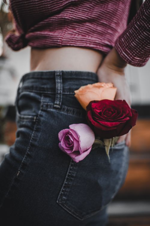 Free Stylish photograph of colorful roses tucked into a denim pocket, showcasing unique fashion details. Stock Photo
