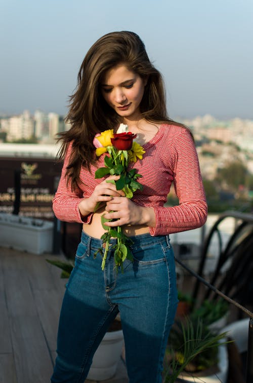 Woman in Red and White Striped Top Holding a Bunch of  Roses