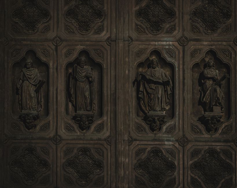 Intricate bronze door featuring detailed sculptures of historical figures, showcasing classic artistry.