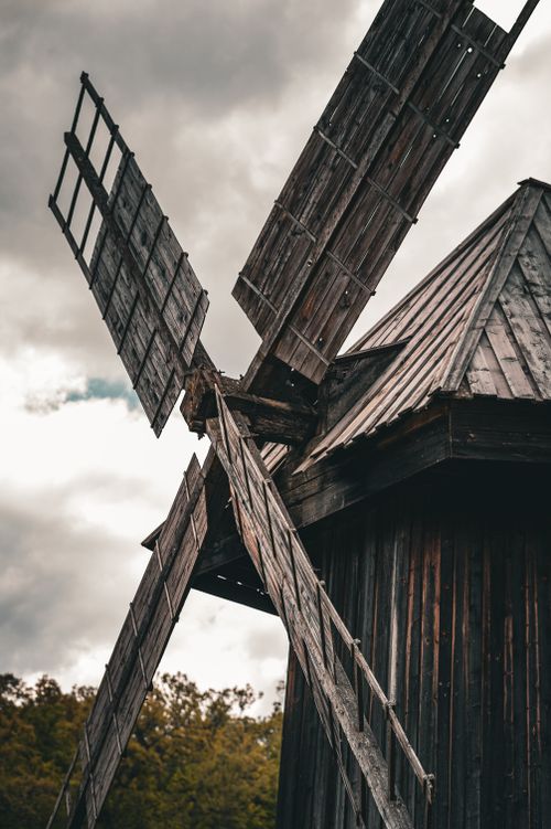 Free Vintage wooden windmill against a dramatic cloudy sky, showcasing rustic architecture and historical charm. Stock Photo