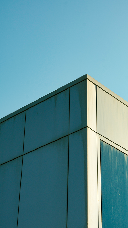 Free Minimalist view of a modern building corner against a blue sky. Stock Photo