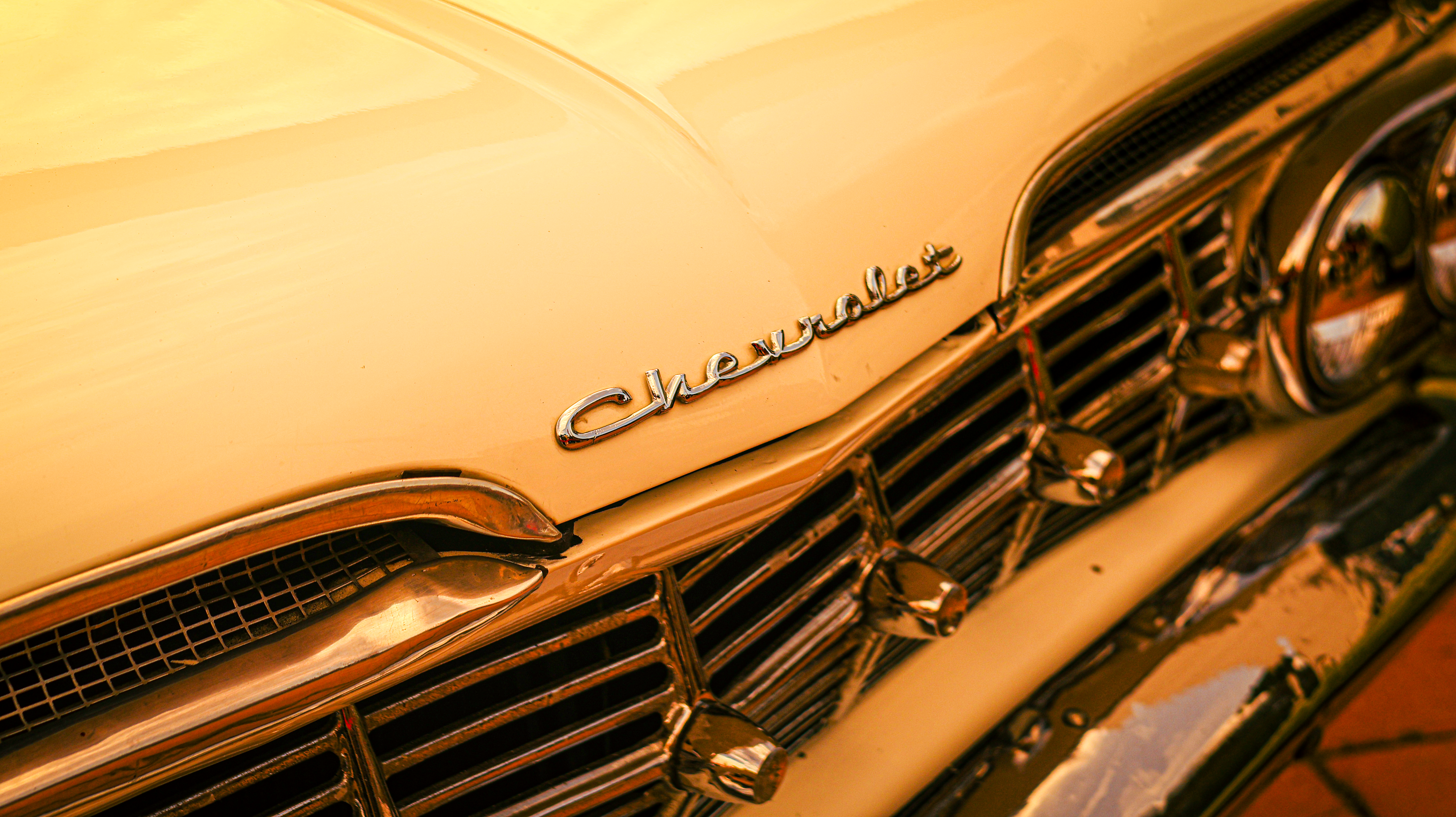 Close-up of a vintage Chevrolet car's front grille and logo with a warm tone.