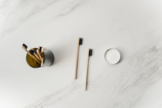 Flat lay of bamboo toothbrushes and powder, showcasing sustainable oral care tools on a marble surface.