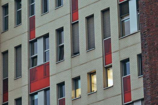 Close-up of a modern building façade in Berlin with red panels and mixed brickwork.