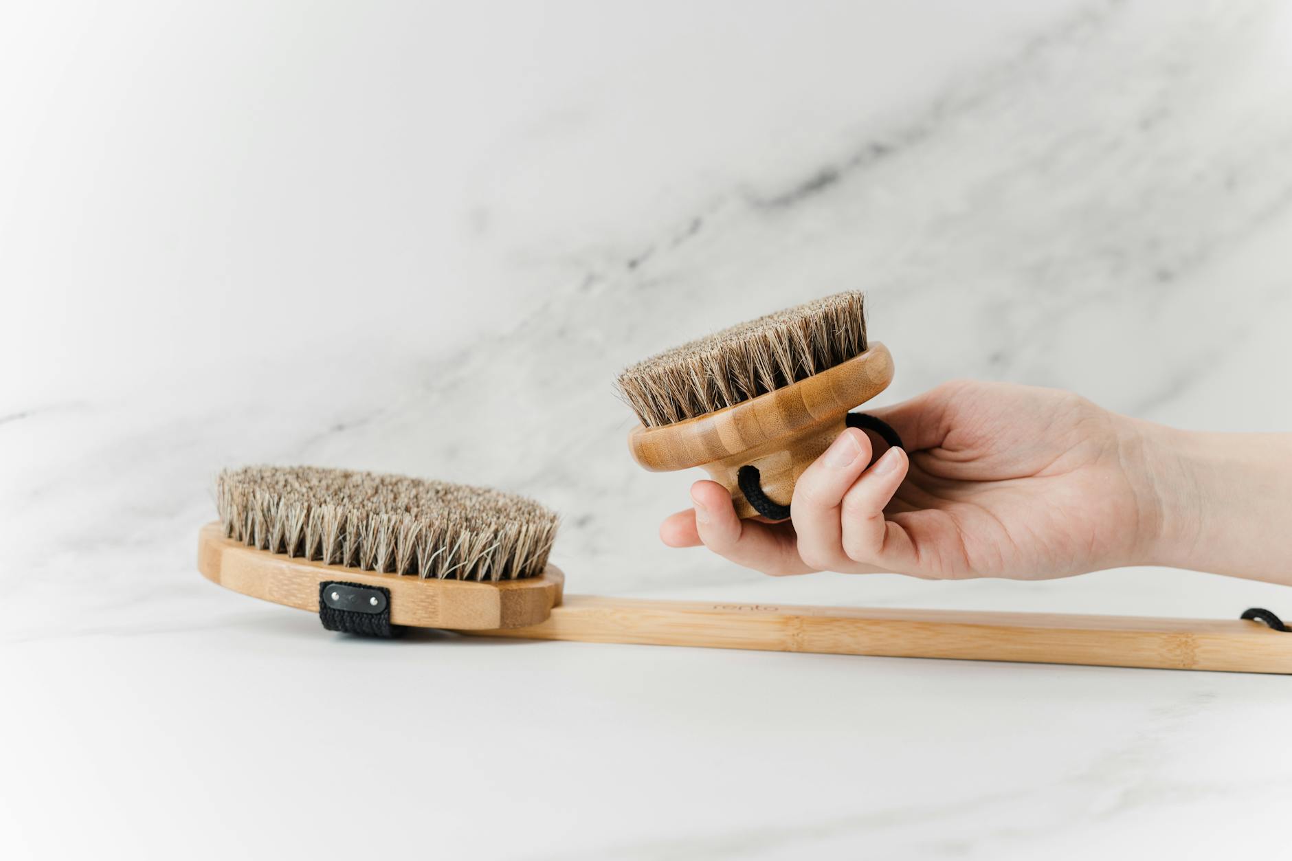 Hand holding an eco-friendly bamboo skincare brush set on a white background.