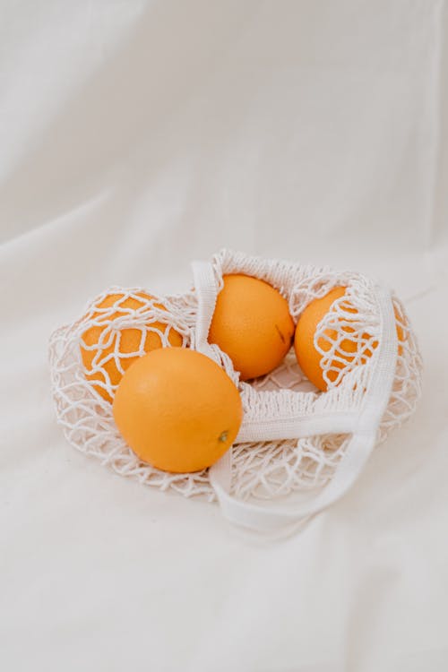 Четыре желтых апельсиновых яйца в белой сетке