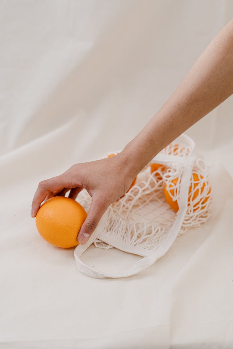 Person Holding Orange Fruit On White Textile