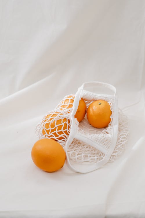Quatre Fruits Orange Sur Un Sac En Filet Blanc