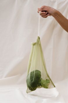 手握装着西兰花的网袋，践行生态友好、零浪费的生活