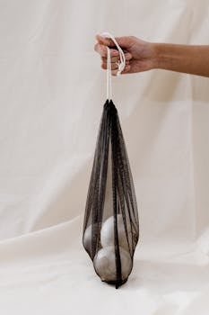 一只手提着装有有机洋葱的网袋，践行零浪费生活