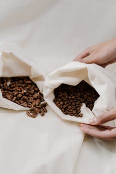 Close-up of hands holding eco-friendly cloth bags filled with coffee beans, promoting sustainability.