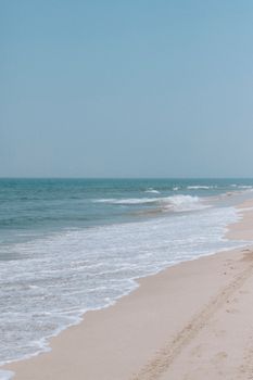 A tranquil sandy beach with gentle waves under a clear blue sky, inviting for relaxation.