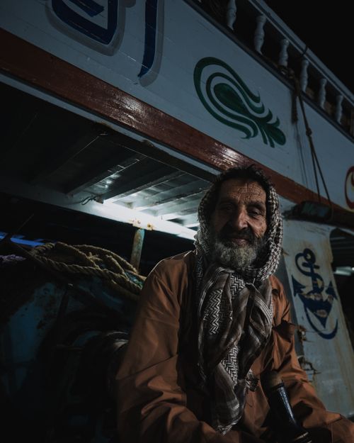 Free A serene portrait of an elderly man in traditional attire aboard a decorated boat at night. Stock Photo