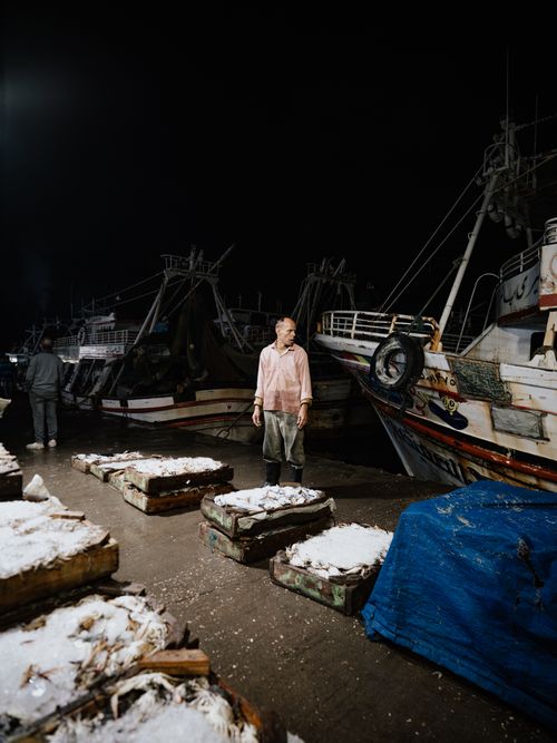 Free Fishermen working at night on busy fishing docks with moored boats and crates of fresh catch. Stock Photo